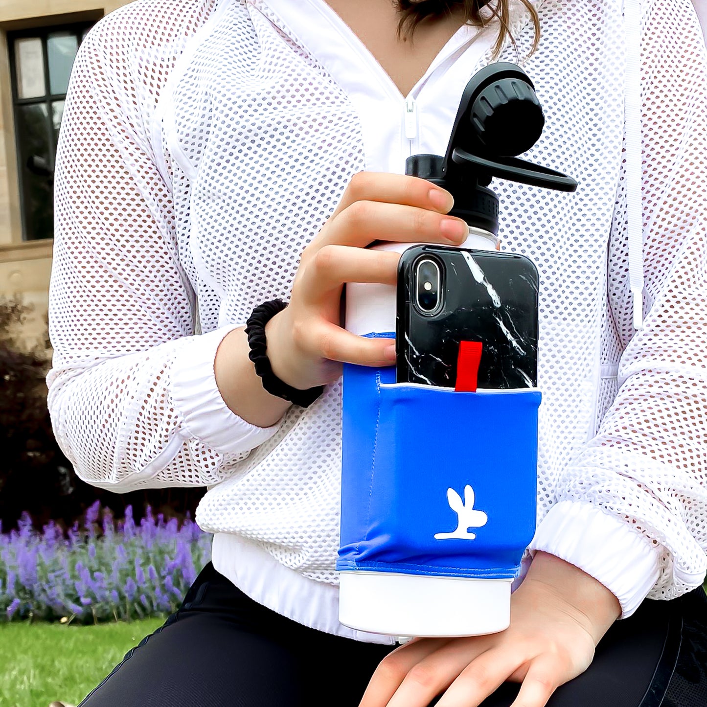 Girl holding a water bottle with a water bottle phone holder.